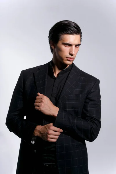 Close up retrato frontal de um belo jovem confiante em terno preto sobre fundo escuro branco. Vista vertical. — Fotografia de Stock