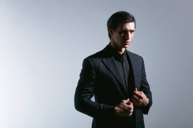 Siyah takım elbiseli yakışıklı bir gencin portresi, gölgesi beyaz arka planda. Metin için boşluk.