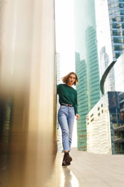 Kısa sarı saçlı, mavi ve kot giyen, günbatımında minimalist şehir tarzı giyinen hoş bir kız..