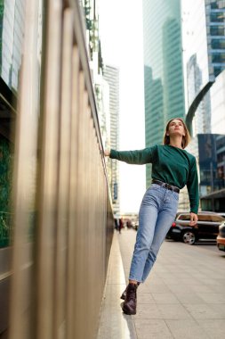 Kısa saçlı havalı bir kız, uzun pozlar veriyor, şehir sokaklarında yürüyor, günbatımında arka planda..