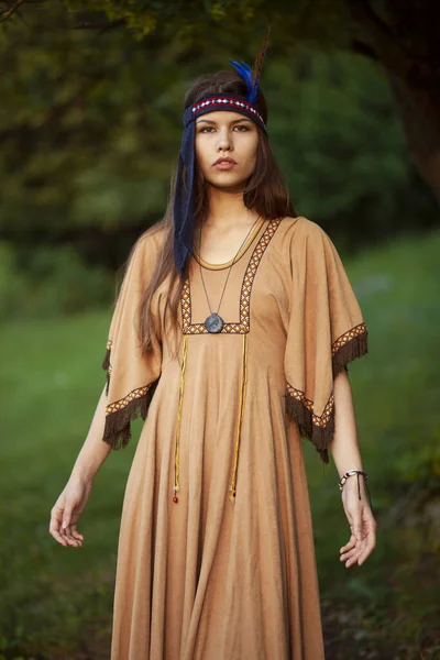 Front closeup portrait of a beautiful young woman in traditional dress, isolated green grass, trees background. — Stock Photo, Image