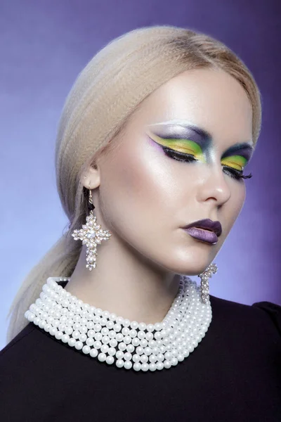 Porträtt av en flicka med blont hår och en mode make-up med slutna ögon, bära pärla halsband och kors örhängen. — Stockfoto