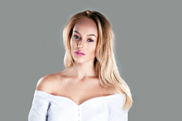 Främre porträtt av sexig blond ung kvinna med vacker makeup, över grå bakgrund. — Stockfoto