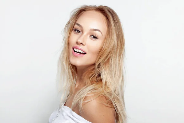 Porträtt av leende blond ung kvinna med vacker naturlig makeup ang långt vågigt hår, över vit bakgrund. — Stockfoto