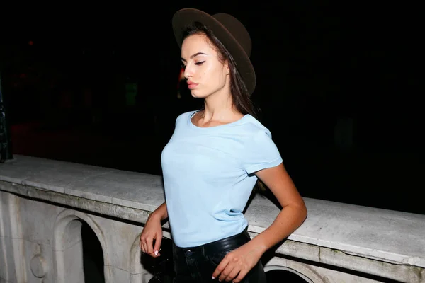Divatos lány kalap, a városban éjjel, megvilágítás, támogatja egy épület, látszó csábító profil. — Stock Fotó