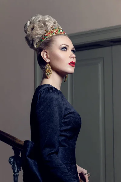 Profil porträtt av en vacker ung kvinna i vacker svart klänning och tillbehör, med makeup, posera på trappan. — Stockfoto