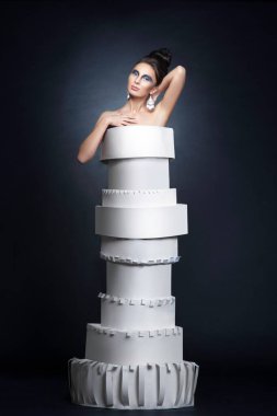 Saç stili ve makyajlı, siyah arka planda kağıt elbise giyen bir kadın modelin tam boy görüntüsü..
