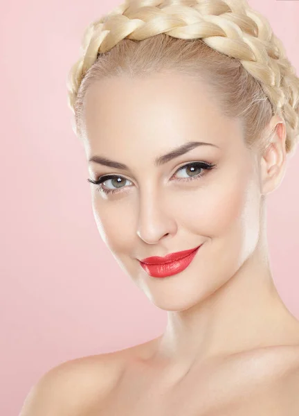 Frontal porträtt av en blond ung kvinna med ljusa make-up och frisyr, med bara schoulders, över rosa bakgrund. — Stockfoto