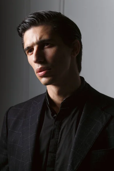 Retrato de close-up de um homem de negócios bonito vestido em terno preto contra um fundo cinza escuro. — Fotografia de Stock