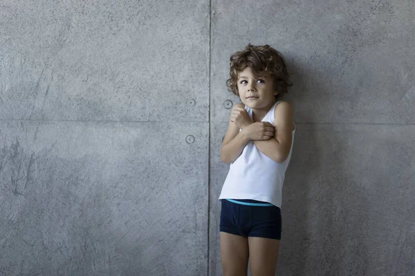 Bonito menino em roupa interior posando na parede de concreto. Espaço para texto. — Fotografia de Stock