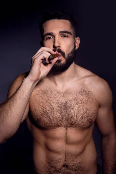 Nahaufnahme Porträt eines brutalen gutaussehenden bärtigen Mannes mit nacktem Oberkörper, der eine Zigarette raucht. Männlicher Schönheitsgehalt. — Stockfoto