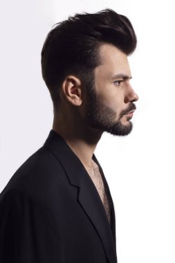 Siyah takım elbiseli, çıplak gövdeli, izole beyaz bir arka planı olan yakışıklı, vahşi, sakallı bir adamın profili..