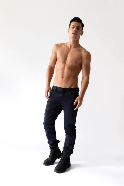 Imagem completa de um jovem com torso pregado em jeans pretos, olhando para a câmera, isolado em um fundo branco. — Fotografia de Stock