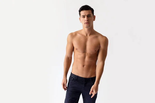 Sexy jovem com torso cortado em jeans pretos, posando em estúdio, olhando para a câmera, isolado em um fundo branco. — Fotografia de Stock