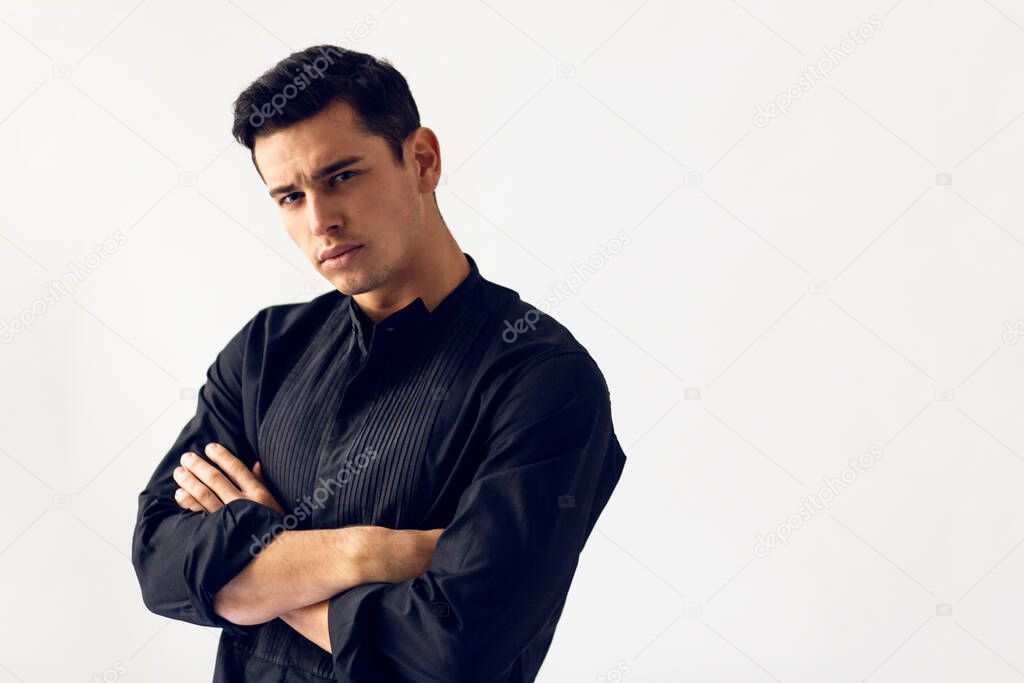 Front portrait of handsome fit young man in black t shirt with cross hands. Copy space.