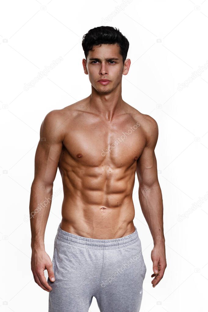 Portrait of a sexy handsome young man with muscular body posing at studio. White background. Mens health.