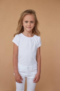 Beyaz elbiseli, dalgalı saçlı, çekingen bir kızın ön portresi. Dikey görünüm.