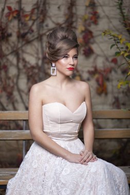 Düğün makyajı ve saç stili ile güzel bir gelinin ön portresi, beyaz elbiseli muhteşem genç kadın..