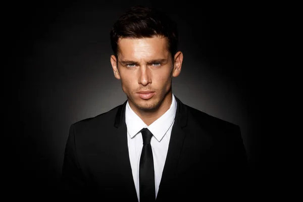 Closeup front portrait of a handsome confident businessman wearing suit standing isolated over black background. — Stock Photo, Image