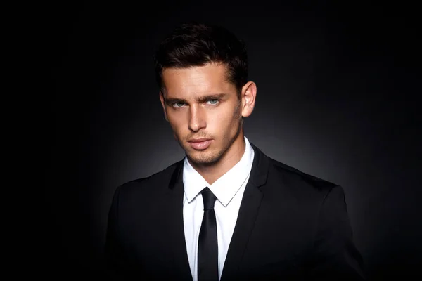 Closeup front portrait of a handsome confident businessman wearing suit standing over black background. — Stock Photo, Image