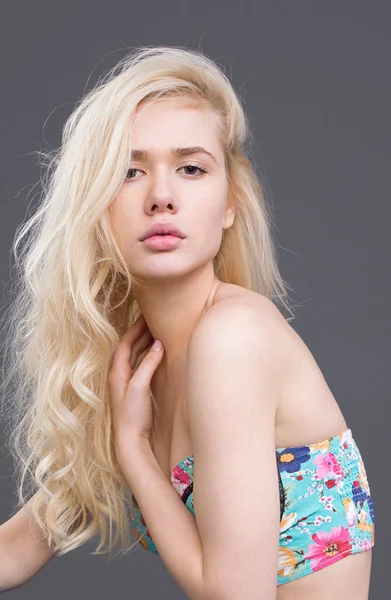 Frontalny portret młodej pięknej blondynki modelki, pozującej w studio, z gołymi ramionami, na szarym tle. — Zdjęcie stockowe