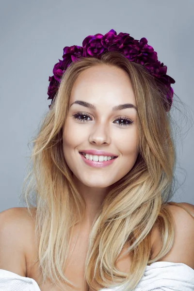 Gros plan portrait de jeune femme blonde souriante avec un beau maquillage, porter des fleurs couronne, sur fond gris. — Photo