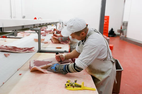 Un grupo de trabajadores en la fábrica de carne, picó una carne fresca de res en pedazos en la mesa de trabajo, alimentos de la industria. — Foto de Stock