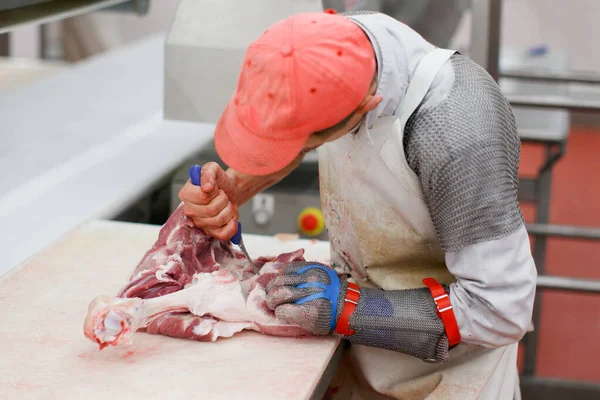 Widok z tyłu pracownika w fabryce mięsa, posiekane świeże mięso wołowe w kawałkach na stole roboczym, żywność przemysłowa. — Zdjęcie stockowe