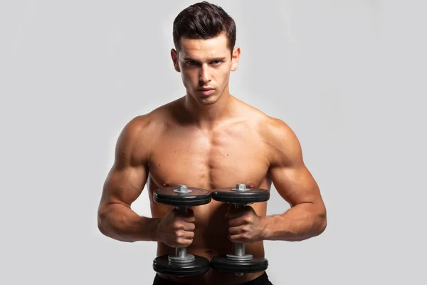 Closeup front portrait of a fit, strong handsome guy with bare torso, training with dumb-bell, isolated white background. Horizontal view. — стоковое фото