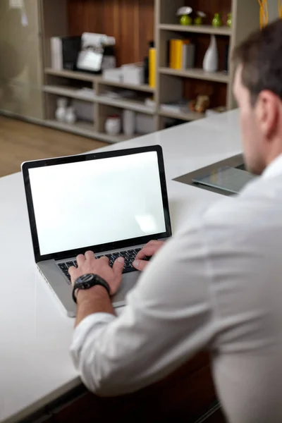 Ofisteki masada otururken dizüstü bilgisayar kullanan sıradan giyinmiş yakışıklı bir adamın arka planı. — Stok fotoğraf
