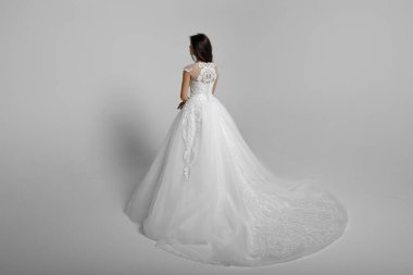 Beyaz bir arka planda izole edilmiş, beyaz gelinlik içinde güzel bir genç kadın. Yatay görünüm.