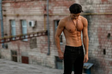 Siyah kot giymiş, tutumuyla poz veren güçlü genç bir sporcu..