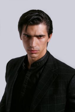 Beyaz arka planda siyah giysili, kendine güvenen yakışıklı bir gencin yakın portresi. Dikey görünüm.