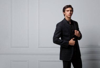 İş adamı neoklasik bir duvara karşı siyah zarif bir takım elbise giyiyor. Yakışıklı bir adamın yakın plan portresi. Yatay görünüm.