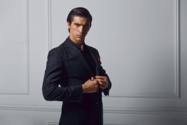 Beyaz arka planda, cebinde kırmızı ipek eşarp olan siyah takım elbiseli, kendinden emin bir gencin ön portresi. Boşluğu kopyala.