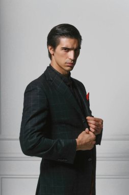 Closeup front portrait of a confident business man in black suit with red silk scarf in pocket, over grey background.