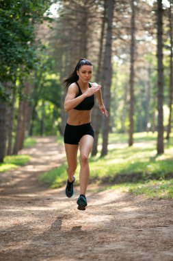 Full length image of a fit young brunette woman running in park, summer, healthy, perfect tone body. Workout outside. Lifestyle concept.