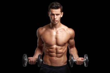 Front image of a fit, strong athletic young man with bare torso, training with dumb-bell, isolated black background.