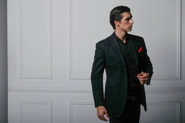 Siyah takım elbiseli, beyaz arka planda kırmızı ipek eşarplı özgüvenli bir gencin portresi..