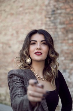 Makyajlı ve saç stili olan neşeli genç bir kadının yakın plan portresi ön kameraya uzanıyor..