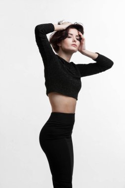 Güzel, seksi, uzun saçlı genç bir kadın, siyah elbiseler giyiyor, aşağı bakıyor, el ele tutuşuyor, beyaz arka planda soyutlanıyor..