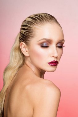 Mükemmel makyajı ve saçı olan, arka tarafı düz, gözleri kapalı, izole pembe arka planı olan genç bir kadının profil portresi..