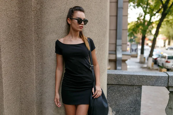 Şehvetli bir kadın model binanın yan tarafına bakıyor ve şehirde yürüyor..