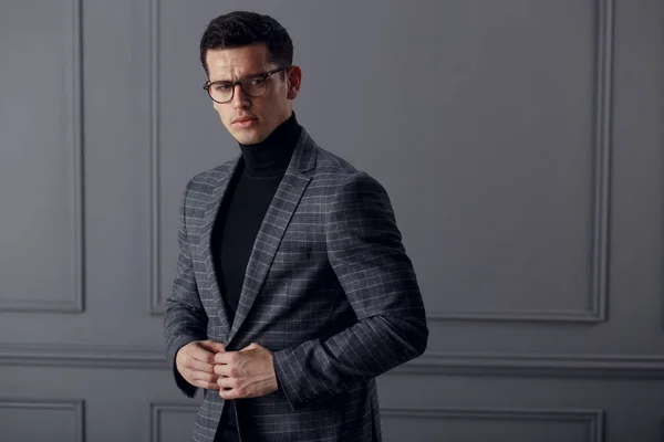 Självsäker, stilig affärsman bär snygg grå kostym och svarta glasögon och ser med attityd på kameran. — Stockfoto