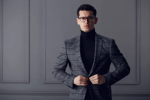 Fiducioso, bell'uomo d'affari in occhiali neri, dolcevita nero e giacca a quadri grigia sembra serio alla telecamera. — Foto Stock