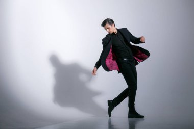 Takım elbiseli atletik bir adam, hareket halinde, beyaz bir arka planda izole edilmiş. Yatay kapalı çekim.