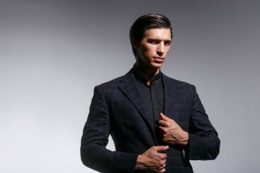 Çekici genç bir adam, kendine güvenen, sadece siyah giyen, sarı arka planda izole edilmiş, kopyalama alanı olan. İş adamı kavramı.