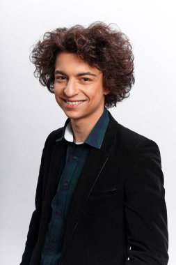 Dalgalı saçlı, gömlekli ve retro ceketli beyaz arka planda kameraya bakan komik adam. Dikey görünüm.