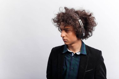 Yatay görüş. Saçları harika, kulaklıklı, düşünceli, beyaz arka planda soyutlanmış üzgün bir gencin profil portresi. Metin için boşluk.