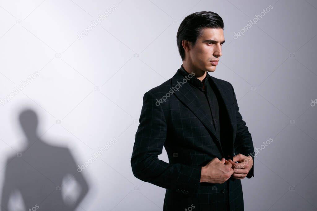 Young handsome man in a stylish suit , arranged his jacket in checkers, isolated on white background.